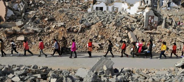 Primary school students walk through the ruins of a demolition area surrounding their school, after class in Zhengzhou, Henan province, China, January 9, 2015. REUTERS/Stringer